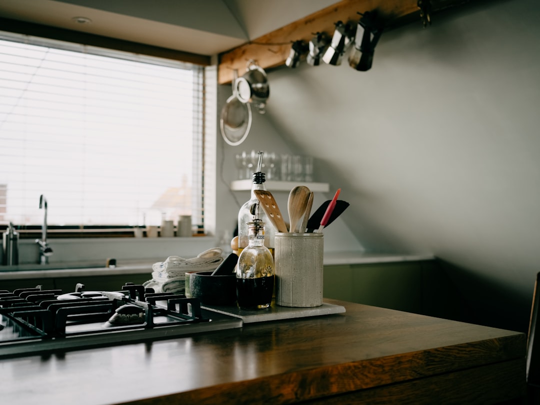 Stainless steel two-slot toaster on a wooden kitchen counter with a soft pastry brush beside it, morning light.
