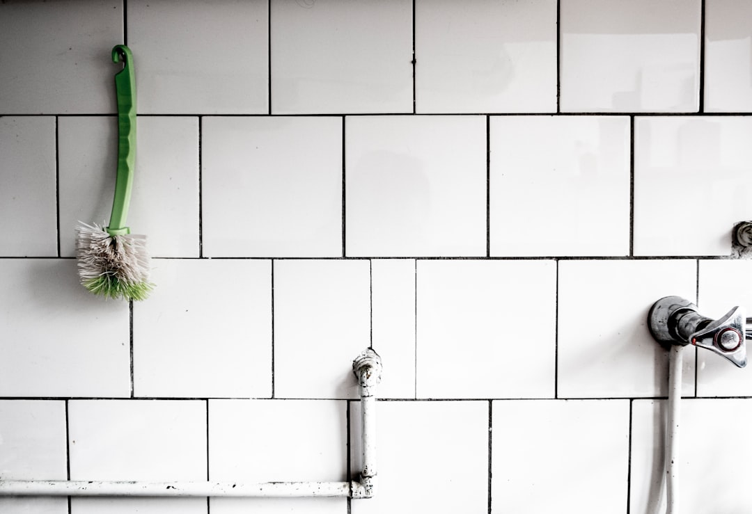 Fresh white bath silicone bead along the edge of a white bath meeting cream ceramic tiles