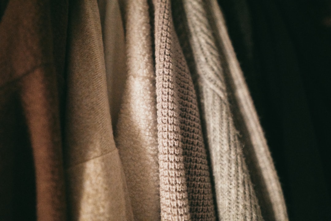Wool winter coats stored on wooden hangers in cotton garment bags inside a cool interior wardrobe